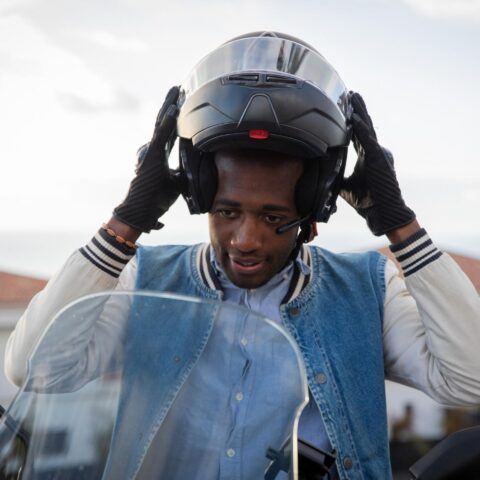 A man puts on his helmet to make sure he follows the Minnesota motorcycle helmet law.